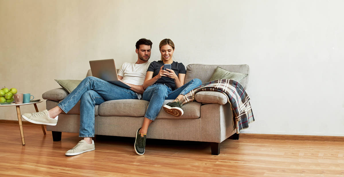 Couple on a sofa using a laptop and phone